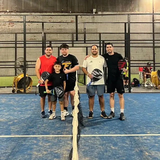 Profes y alumnos, grandes y chicos, posando con paletas en la cancha azul